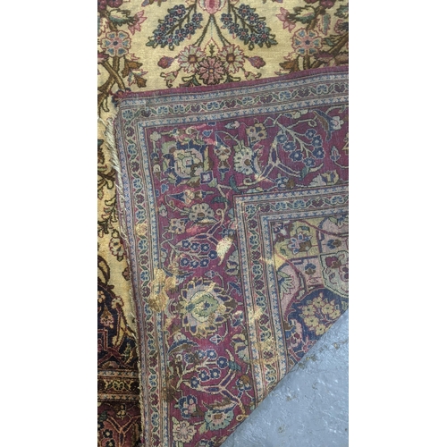 583 - A handwoven Persian silk rug on beige ground and red border decorated with flowers in a vase, surrou... 