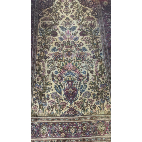 583 - A handwoven Persian silk rug on beige ground and red border decorated with flowers in a vase, surrou... 