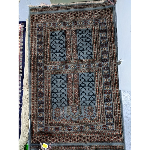 574 - Two Persian machine woven rugs with floral decoration on blue grounds, along with an Indian handwove... 