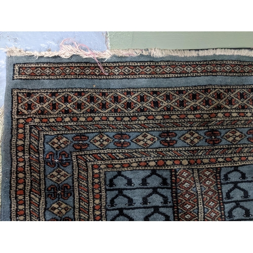 574 - Two Persian machine woven rugs with floral decoration on blue grounds, along with an Indian handwove... 