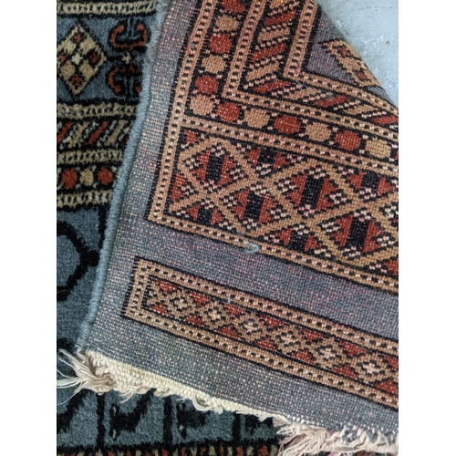 574 - Two Persian machine woven rugs with floral decoration on blue grounds, along with an Indian handwove... 