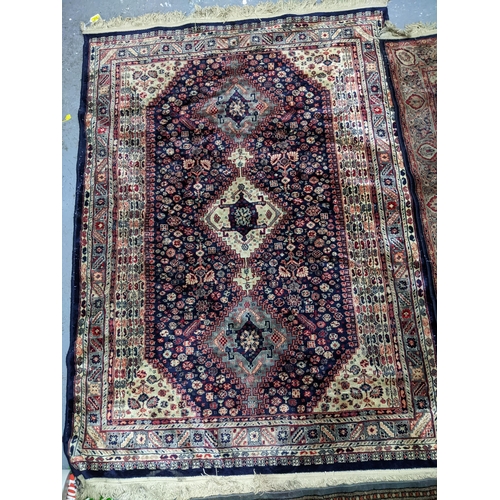 574 - Two Persian machine woven rugs with floral decoration on blue grounds, along with an Indian handwove... 