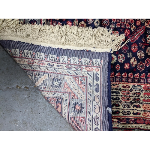 574 - Two Persian machine woven rugs with floral decoration on blue grounds, along with an Indian handwove... 