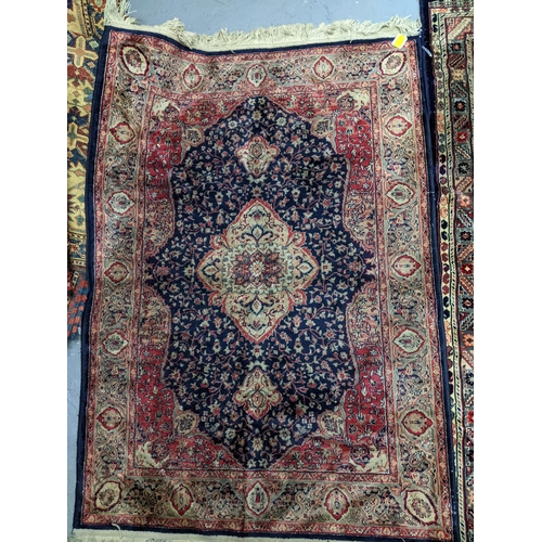 574 - Two Persian machine woven rugs with floral decoration on blue grounds, along with an Indian handwove... 