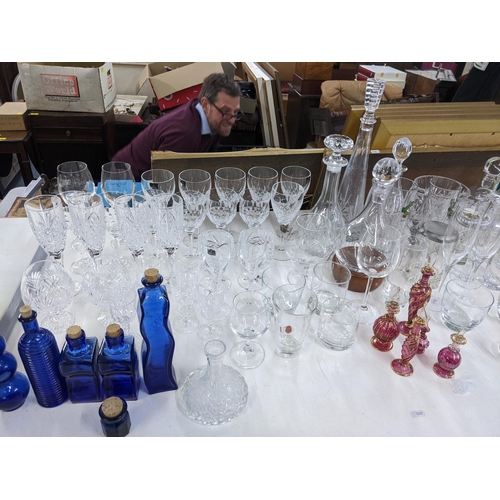 576 - A collection of glassware to include crystal cut decanters, wine glasses, a collection of blue art g... 