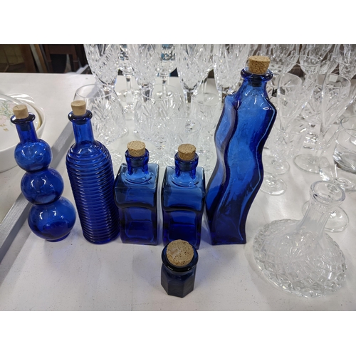 576 - A collection of glassware to include crystal cut decanters, wine glasses, a collection of blue art g... 