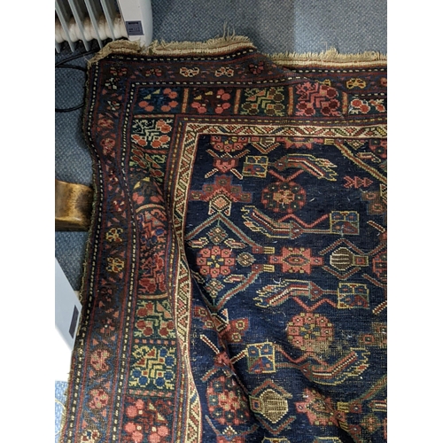 597 - Two Persian rugs to include one with a symmetrical repeating design on a dark blue background and an... 