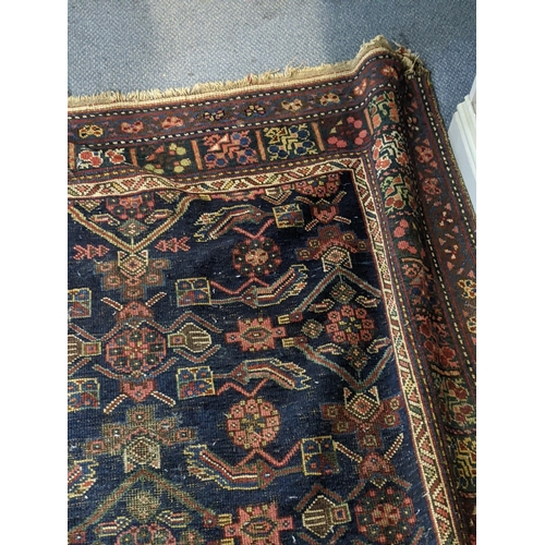 597 - Two Persian rugs to include one with a symmetrical repeating design on a dark blue background and an... 