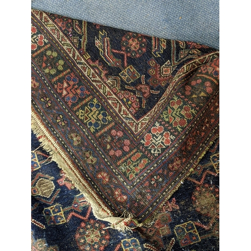 597 - Two Persian rugs to include one with a symmetrical repeating design on a dark blue background and an... 