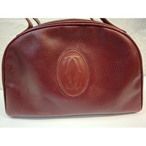 14 - Must de Cartier- A late 20th Century burgundy leather handbag in the bowling bag style having gold t... 