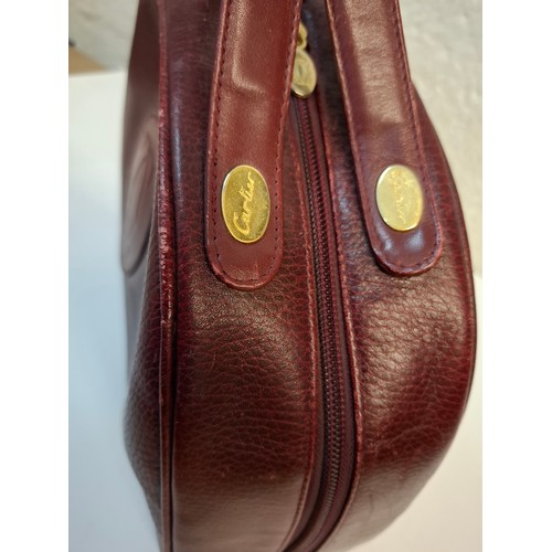 14 - Must de Cartier- A late 20th Century burgundy leather handbag in the bowling bag style having gold t... 