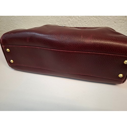 14 - Must de Cartier- A late 20th Century burgundy leather handbag in the bowling bag style having gold t... 