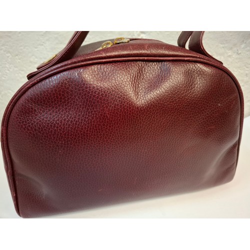 14 - Must de Cartier- A late 20th Century burgundy leather handbag in the bowling bag style having gold t... 