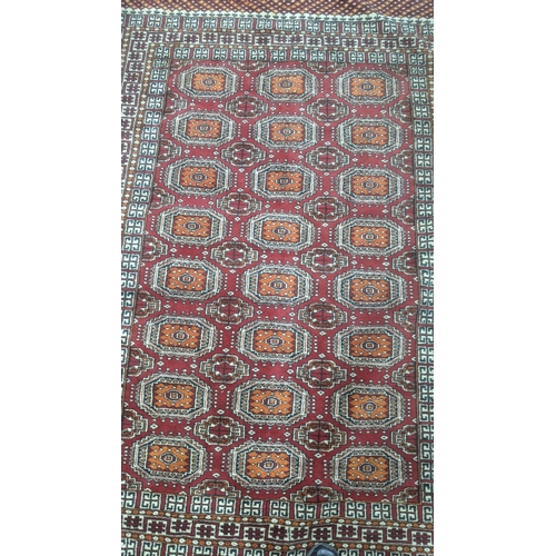 345 - A handwoven Bokha rug on ed ground with repeating motifs and repeating pattern to the centre with ta... 