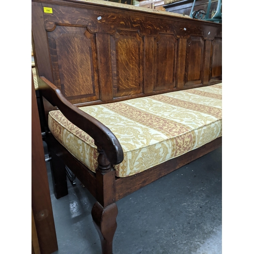 346 - A Georgian oak settle, five fielded panelled back, open arms, loose upholstered cushion seat, on fro... 