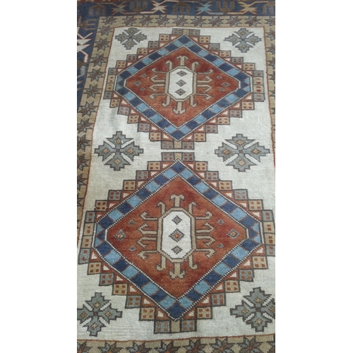 435 - A Turkish hand woven rug having repeating motifs cream ground with multi guard borders and tasselled... 