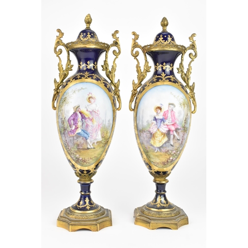 121 - A pair of late 19th century Sevres style lidded vases, each on a dark blue ground with gilded scroll... 