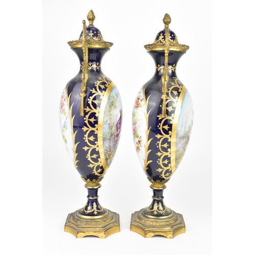 121 - A pair of late 19th century Sevres style lidded vases, each on a dark blue ground with gilded scroll... 