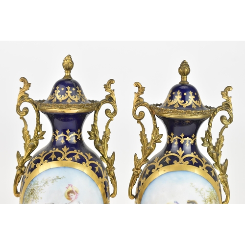 121 - A pair of late 19th century Sevres style lidded vases, each on a dark blue ground with gilded scroll... 