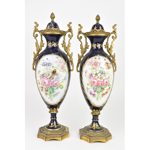 121 - A pair of late 19th century Sevres style lidded vases, each on a dark blue ground with gilded scroll... 