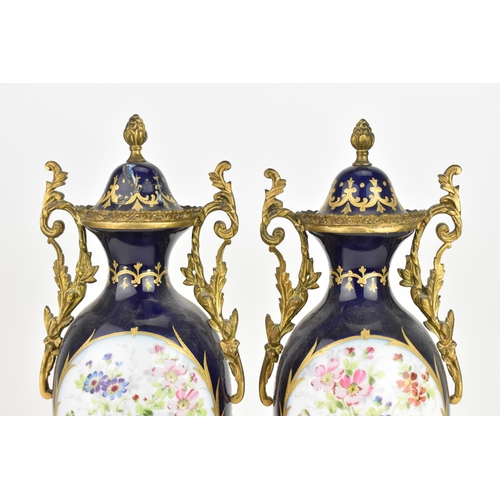 121 - A pair of late 19th century Sevres style lidded vases, each on a dark blue ground with gilded scroll... 