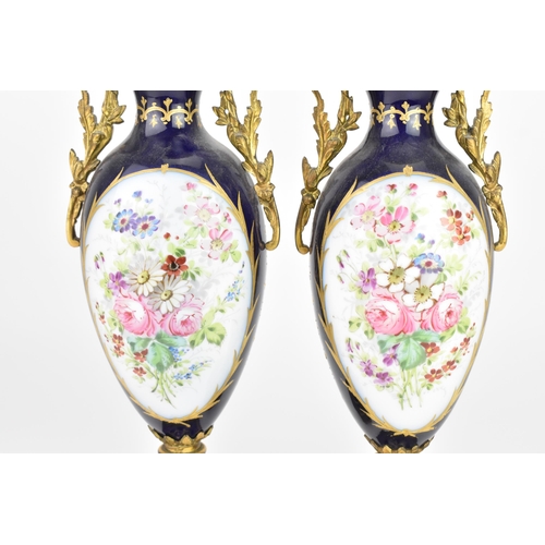 121 - A pair of late 19th century Sevres style lidded vases, each on a dark blue ground with gilded scroll... 