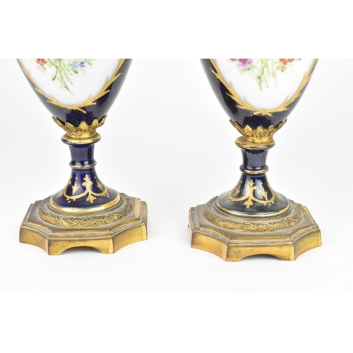 121 - A pair of late 19th century Sevres style lidded vases, each on a dark blue ground with gilded scroll... 