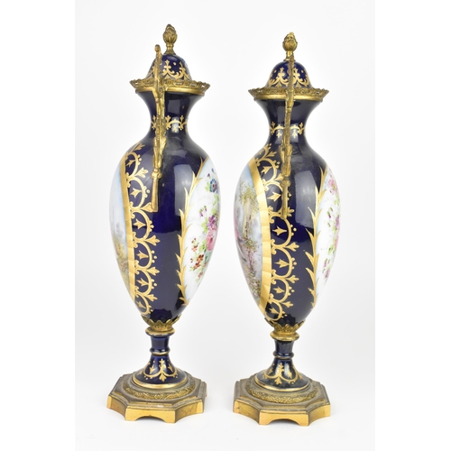 121 - A pair of late 19th century Sevres style lidded vases, each on a dark blue ground with gilded scroll... 