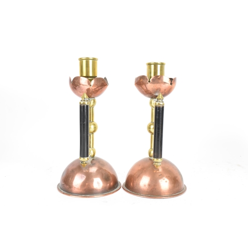 17 - A Pair of Arts and Crafts copper and brass candlesticks in the manner of Christopher Dresser for Ben... 