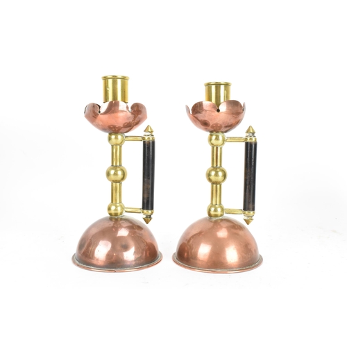 17 - A Pair of Arts and Crafts copper and brass candlesticks in the manner of Christopher Dresser for Ben... 