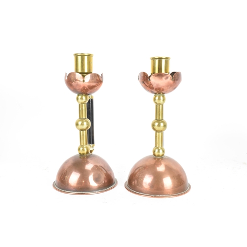 17 - A Pair of Arts and Crafts copper and brass candlesticks in the manner of Christopher Dresser for Ben... 