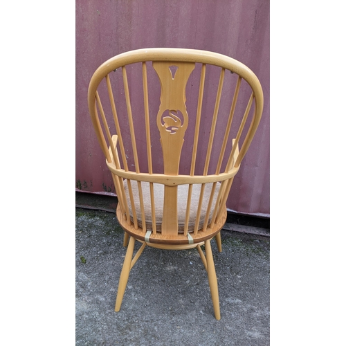 50A - A vintage Ercol light elm and beech 'Swan Back' armchair, with turned legs united by a crinoline str... 