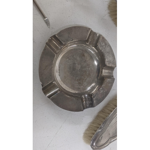 63 - A group of silver to include an ashtray, dressing table items including brushes A/F, silver handled ... 