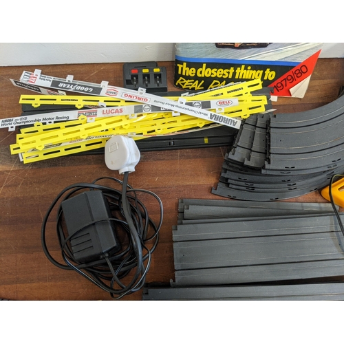 21 - An Aurora World Championship Motor Racing set with two remote controllers, four cars, track, and pla... 