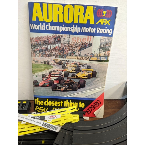 21 - An Aurora World Championship Motor Racing set with two remote controllers, four cars, track, and pla... 