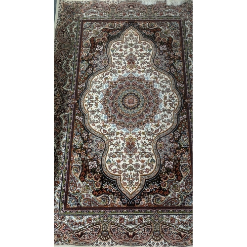 36 - A Persian machine woven rug on cream ground with repeating central motifs and floral boarders and ta... 