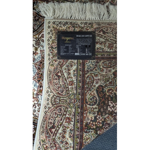 36 - A Persian machine woven rug on cream ground with repeating central motifs and floral boarders and ta... 