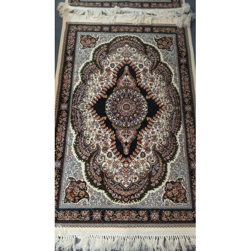 40 - A pair of Persian machine woven rugs on cream ground with central motifs and floral borders with tas... 