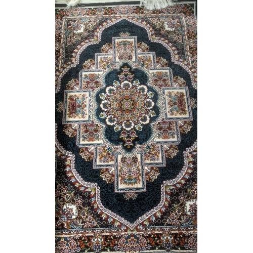 41 - A Persian machine woven rug on black ground with repeating central motifs and floral boarder with ta... 