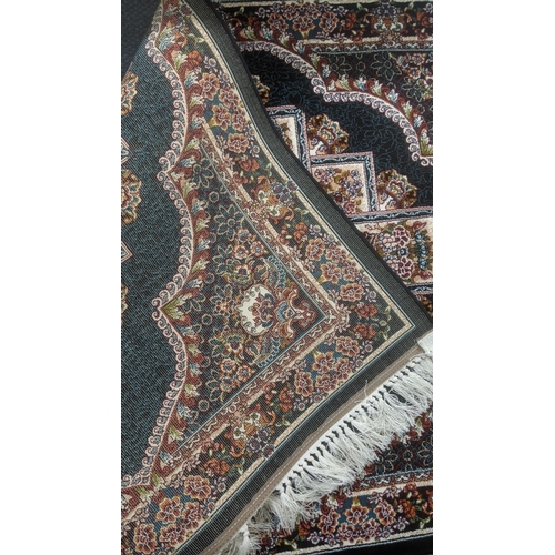 41 - A Persian machine woven rug on black ground with repeating central motifs and floral boarder with ta... 