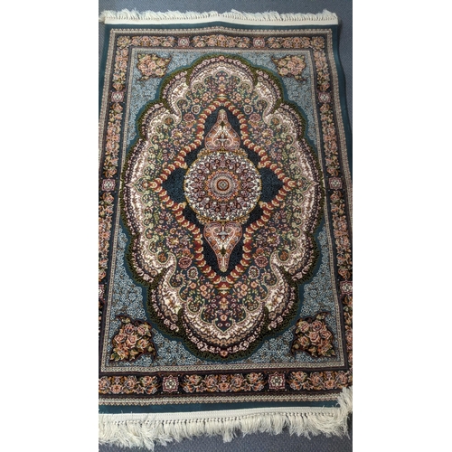 50 - A Persian machine woven rug on green ground with repeating motifs, floral decoration and floral bord... 