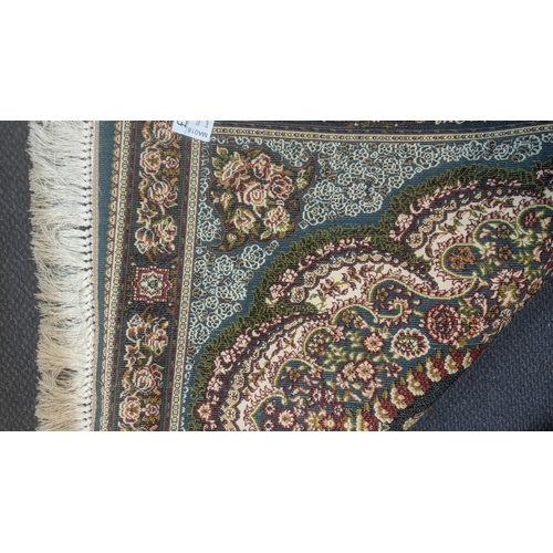 50 - A Persian machine woven rug on green ground with repeating motifs, floral decoration and floral bord... 