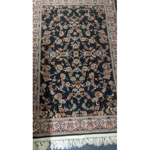 51 - A Persian machine woven rug on black ground with floral design to the centre and floral boarder and ... 