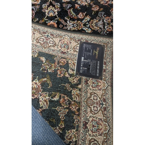 51 - A Persian machine woven rug on black ground with floral design to the centre and floral boarder and ... 