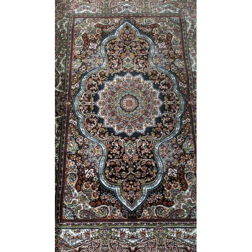 56 - A Persian machine woven rug on black ground with repeating central motifs and floral boarders with t... 