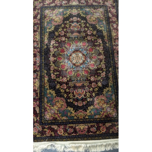 60 - A Persian machine woven rug on black ground with central motifs, repeating borders and floral decora... 