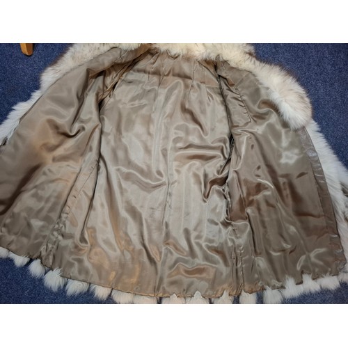 54 - A 1980's arctic fox jacket having intermittent vertical leather stripes, shawl collar and brown sati... 