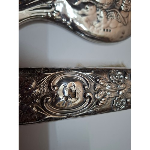 48 - A silver 2-piece dressing table set featuring a cherubic design together with a silver clothes brush... 