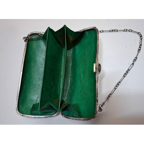 32 - An early 20th Century silver evening purse with green leather interior having hand engraved floral s... 