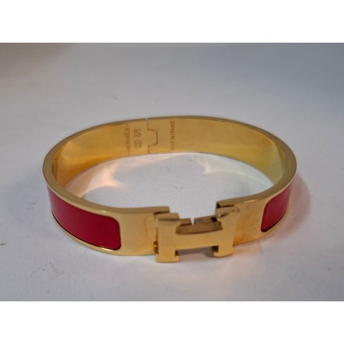 Hermes- A 'Clic H' gold plated and red enamel bracelet, made in France, internal measurement 18cm. Location:Cab
